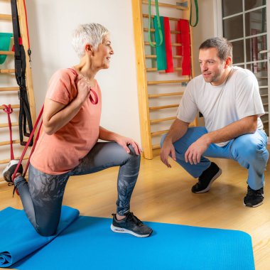 Spor salonunda lastik bantla egzersiz yapan son sınıf öğrencisi bir kadın. 