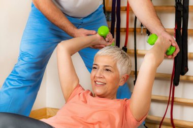 Pilates topunda antrenman yapan yaşlı kadın koçlara yardım ediyor. 