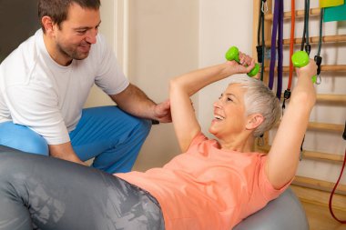 Pilates topunda antrenman yapan yaşlı kadın koçlara yardım ediyor. 