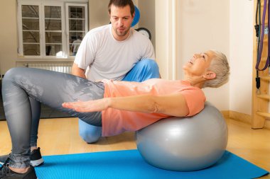 Pilates topunda antrenman yapan yaşlı kadın koçlara yardım ediyor. 
