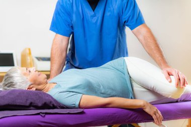 Klinikte kıdemli bir hastayla çalışan fizyoterapist.