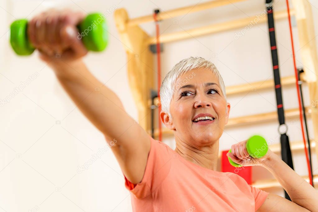 Portrait of senior woman exercising with dumbbells