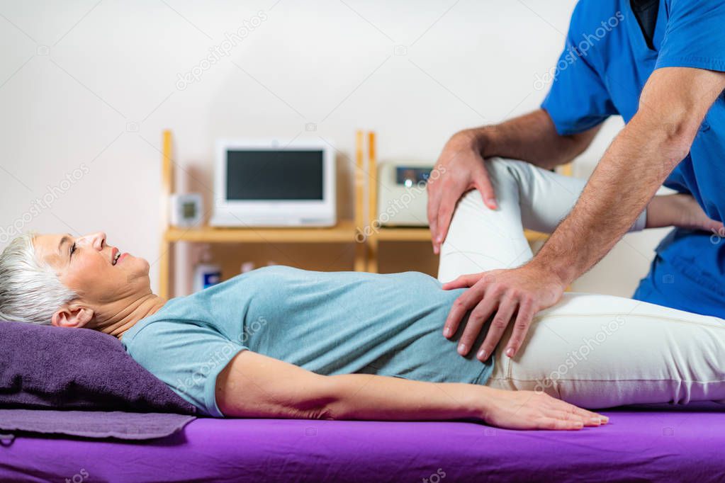 Physical Therapist Working with Leg. Senior Woman