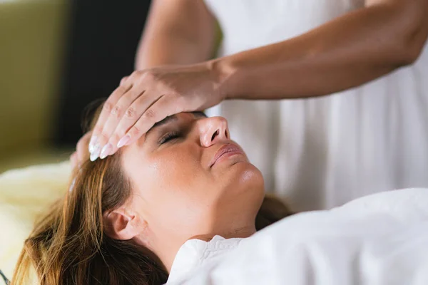 Reiki Therapist Transferring Energy. Peaceful Woman Lying with Her Eyes Closed.