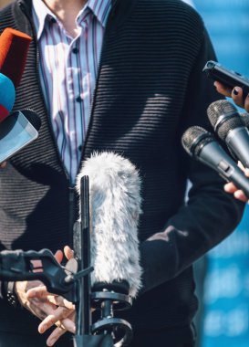 Gazeteciler erkek konuşmacı ve mikrofon ve cep telefonu ile röportaj yapıyorlar.