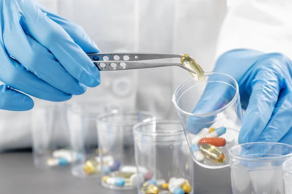 Gyógyszerek Válogatása Doktorok Kezébe Kék Kesztyű Kerül Csipeszes Gyógyszerekkel Szemüvegben — Stock Fotó