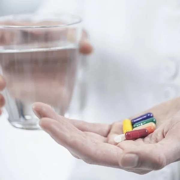 Läkares Hand Håller Färgglada Piller Och Glas Vatten — Stockfoto