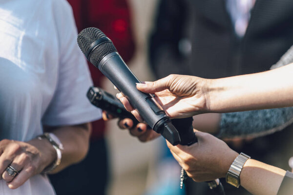 Journalists holding microphone and dictaphone, interviewing female speaker.