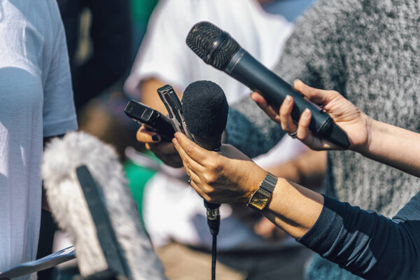 Journalists holding microphone and dictaphone, interviewing female speaker.