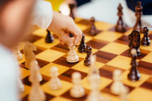 School boys playing chess.  Sitting at the table, looking at the board, thinking intensely.