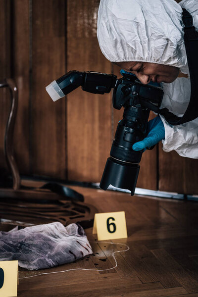 Полицейский криминалист фотографирует место преступления, собирает улики
