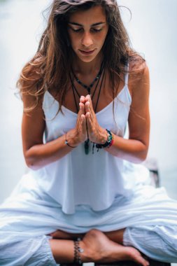 Genç kadın meditasyon yapıyor, doğada yoga yapıyor. Nilüfer çiçeğinde ellerin dua pozisyonunda oturuyor..
