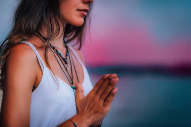 Genç bir kadın gözleri kapalı meditasyon yapıyor. Elleri dua pozisyonunda yoga yapıyor..  