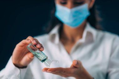 Covid-19 Coronavirus Salgını Önleme. Güzel genç kadın ellerini dezenfekte ediyor, el dezenfekte jeli kullanıyor.