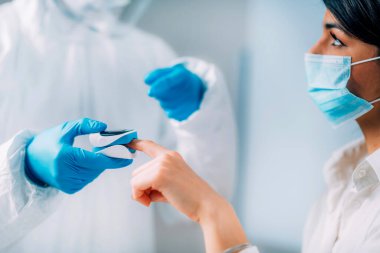 Coronavirus belirtileri. Sıhhiyeci kan oksijeni seviyesini oksimetreyle ölçüyor. Hasta koruyucu maske takıyor.