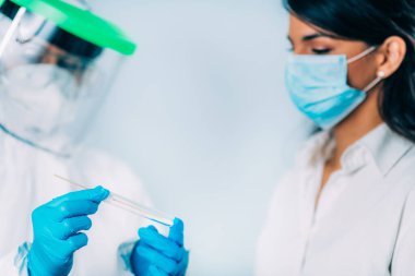 Coronavirus testi. Koruyucu süitte, Corona virüsü testi için örnek alan, potansiyel olarak enfekte olmuş genç bir kadın. 