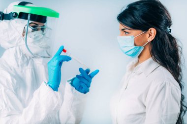 Coronavirus testi. Koruyucu süitte, Corona virüsü testi için örnek alan, potansiyel olarak enfekte olmuş genç bir kadın. 