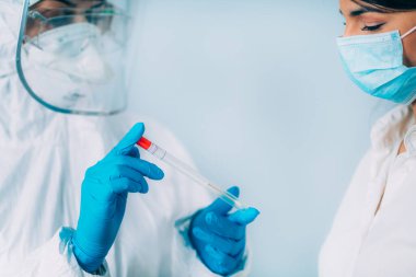 Coronavirus testi. Koruyucu süitte, Corona virüsü testi için örnek alan, potansiyel olarak enfekte olmuş genç bir kadın. 