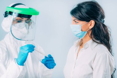Coronavirus testi. Koruyucu süitte, Corona virüsü testi için örnek alan, potansiyel olarak enfekte olmuş genç bir kadın. 