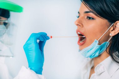 Coronavirus testi. Koruyucu süitte, Corona virüsü testi için örnek alan, potansiyel olarak enfekte olmuş genç bir kadın. 
