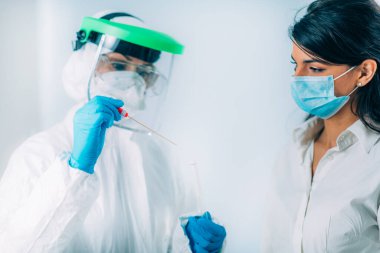 Coronavirus testi. Koruyucu süitte, Corona virüsü testi için örnek alan, potansiyel olarak enfekte olmuş genç bir kadın. 