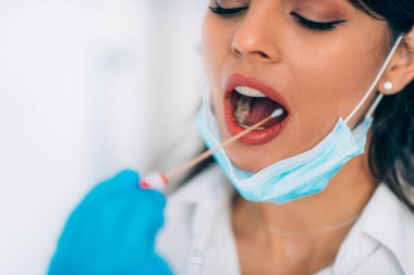 Coronavirus testi. Koruyucu süitte, Corona virüsü testi için örnek alan, potansiyel olarak enfekte olmuş genç bir kadın. 