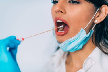 Coronavirus testi. Koruyucu süitte, Corona virüsü testi için örnek alan, potansiyel olarak enfekte olmuş genç bir kadın. 