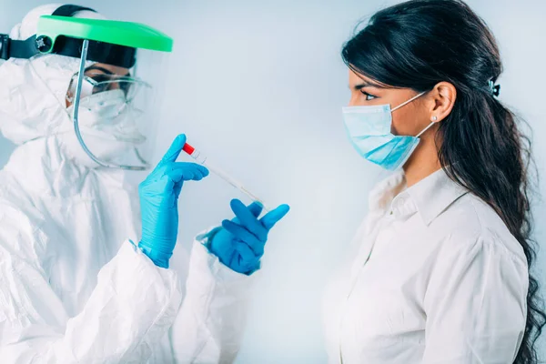 Coronavirus testi. Koruyucu süitte, Corona virüsü testi için örnek alan, potansiyel olarak enfekte olmuş genç bir kadın. 