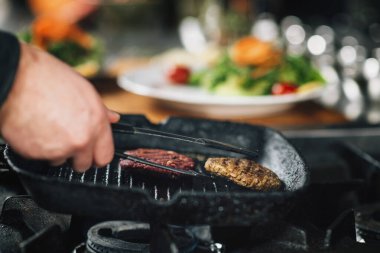 Restoranda yemek pişirmek. Bir şefin el yapımı vejetaryen hamburgerinin yakın çekimi.  