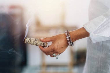 Duman tüten adaçayı çubuğu tutan ruhani bir kadının elleri.