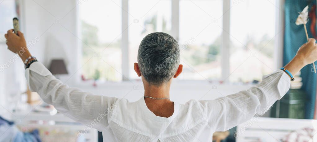 Woman performing ritual of sage burning to cleanse space from negative energy. Physical, mental, and emotional well-being.