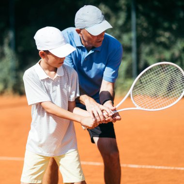 Gülümseyen Tenis koçu Tenis oynamayı öğretiyor. Clay Court 'ta Tenis Dersi.