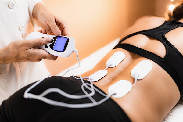Lower Back Physical Therapy with TENS Electrode Pads, Transcutaneous Electrical Nerve Stimulation. Electrodes onto Patient's Lower Back