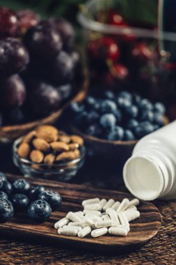 Trans-Pterostilbene takviyeleri. Antioksidan besinlerle çevrili. Yaban mersini, kırmızı üzüm ve badem. Yakın çekim, takviyeye odaklan.
