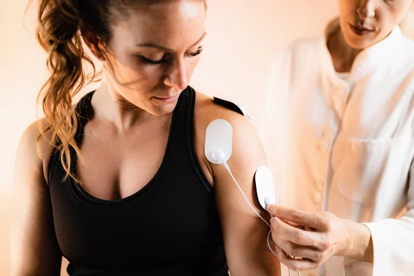 Shoulder Physical Therapy with TENS Electrode Pads, Transcutaneous Electrical Nerve Stimulation. Therapist Positioning Electrodes onto Patient's Shoulder