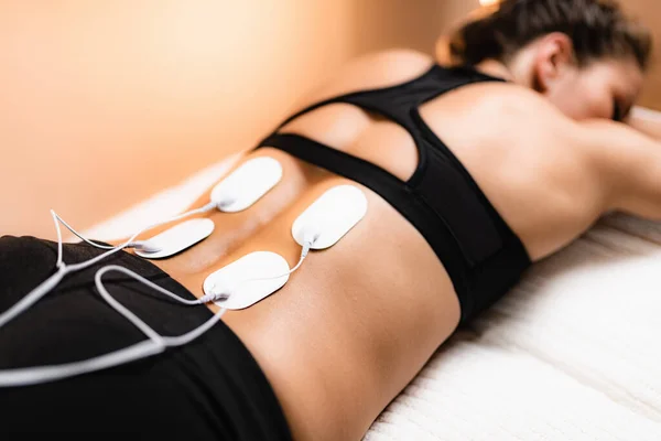 Lower Back Physical Therapy with TENS Electrode Pads, Transcutaneous Electrical Nerve Stimulation. Electrodes onto Patient's Lower Back