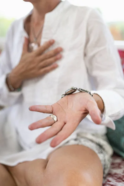 Receiving Energy Hand Gesture.  Woman sitting in a lotus position with left palm raised upward to receive positive energy.