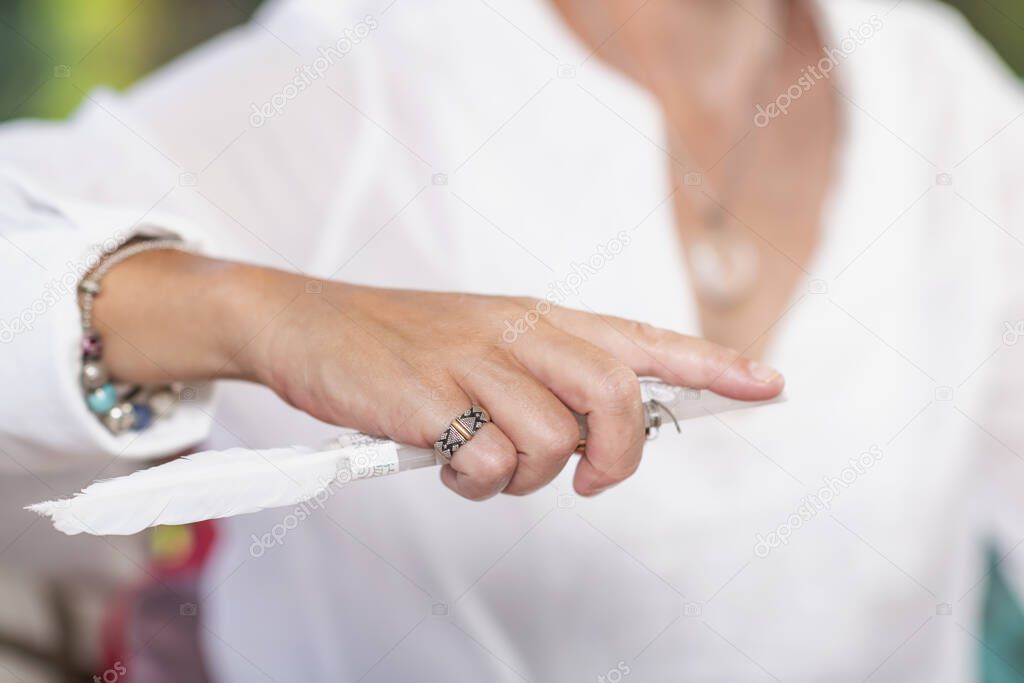 Guardian angel virtue,woman  hand of a spiritual healer holding a crystal with white feather. Alternative healing 