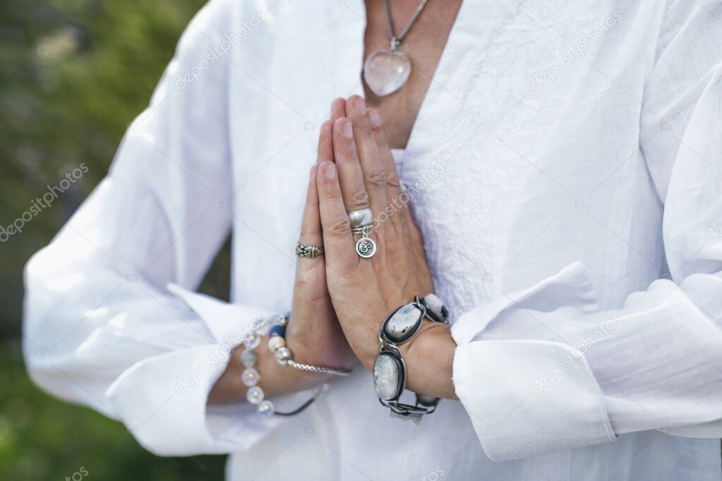 Close up image of female hands in prayer position outdoor. Self-care practice for wellbeing