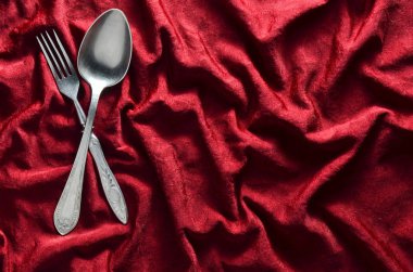Kaşık ve çatal kırmızı ipek masa örtüsü üzerinde. Vintage çatal bıçak takımı. Uzay kopyalayın. Üstten Görünüm.