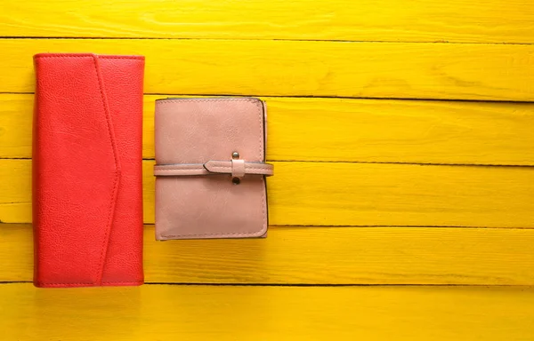De portemonnee van de twee vrouwen op een gele houten achtergrond. Trend accessoires. Kopieer ruimte. Bovenaanzicht. — Stockfoto