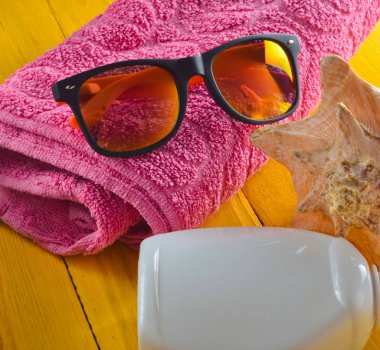 Beach resort konsepti. Mavi sarı ahşap arka plan üzerinde kadın plaj aksesuarları. Kabuk, gözlük, havlu, güneş kremi.