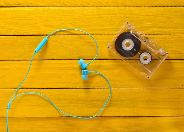 Het concept van liefde voor muziek. Hoofdtelefoon, audio cassette op een gele houten tafel. Bovenaanzicht. — Stockfoto