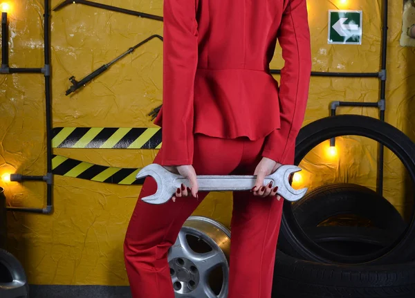 Menina mecânica elegante em roupas da moda está segurando uma chave no fundo da oficina de um mecânico de automóveis. Tiro de moda, uma imagem incomum. Estilo de vida . — Fotografia de Stock