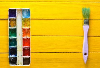 Suluboya boya ve resim sarı bir ahşap kurullarında için bir fırça palet. Üstten Görünüm. Uzay kopyalayın. Sanat kavramı