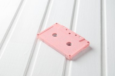 Beyaz ahşap bir masa üzerinde pembe pastel ses kaset. Retro medya teknoloji.