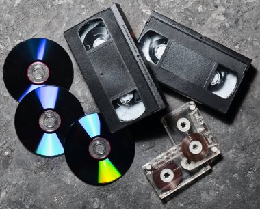 Eğlence ve medya teknoloji 90s. CD, kaset, video kasetleri üzerinde siyah bir beton yüzey. Üstten görünüm. Işık pop.