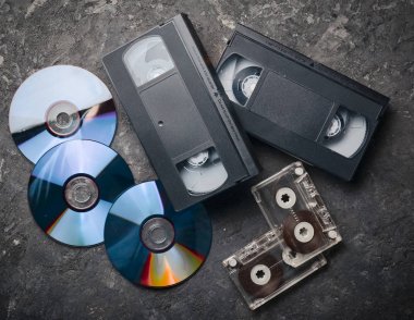 Eğlence ve medya teknoloji 90s. CD, kaset, video kasetleri üzerinde siyah bir beton yüzey. Üstten Görünüm.
