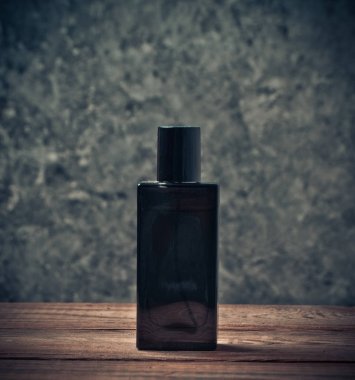 Bir ahşap raf bir gri beton duvara bir parfüm şişesi.