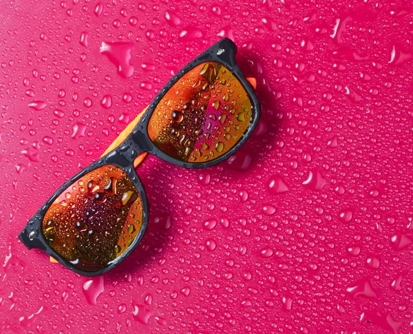 Óculos de sol de moda em baixas de água em um fundo rosa brilhante. Vista superior . — Fotografia de Stock